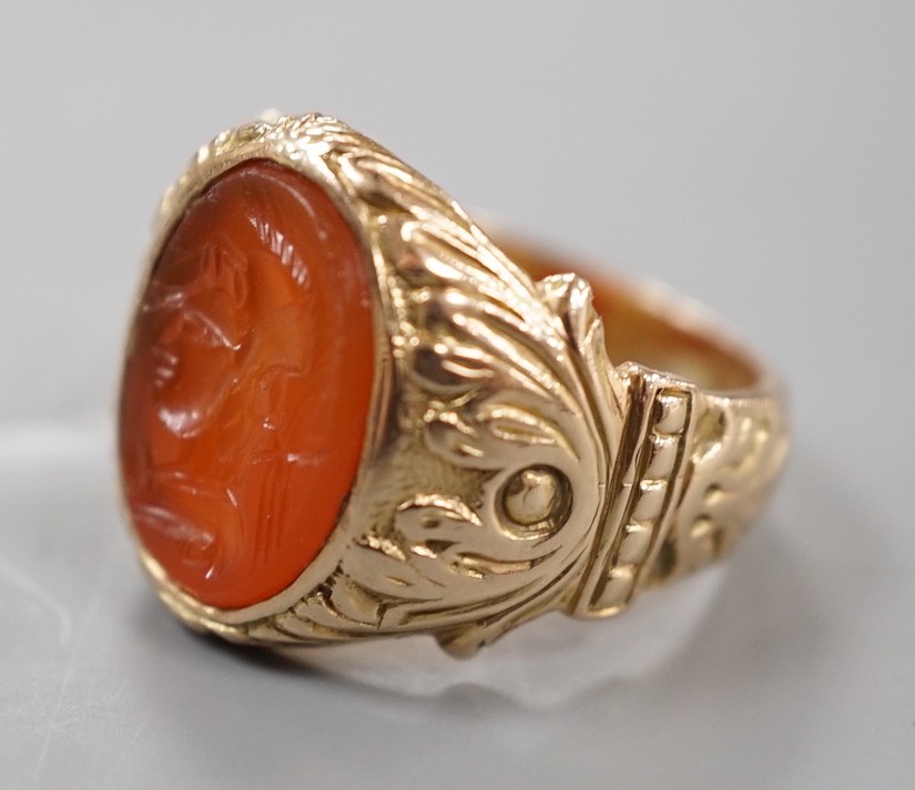 An early 20th century yellow metal and intaglio carnelian set signet ring, the matrix carved with the bust of a Roman soldier, with carved setting and shank, size M, gross weight 9.6 grams.